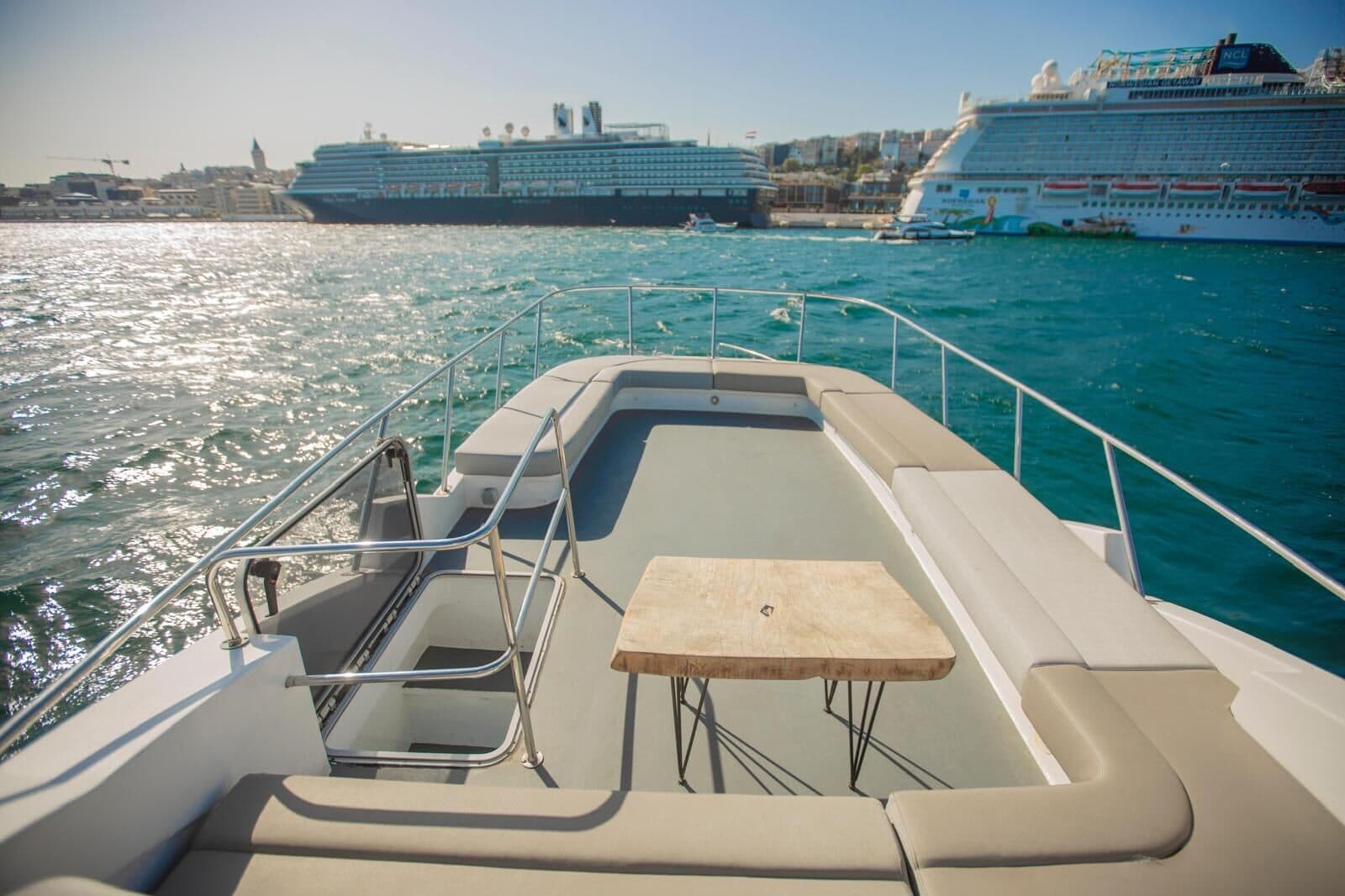 Deck seating and a table on a Luma charter yacht, cruise ships at Galataport behind