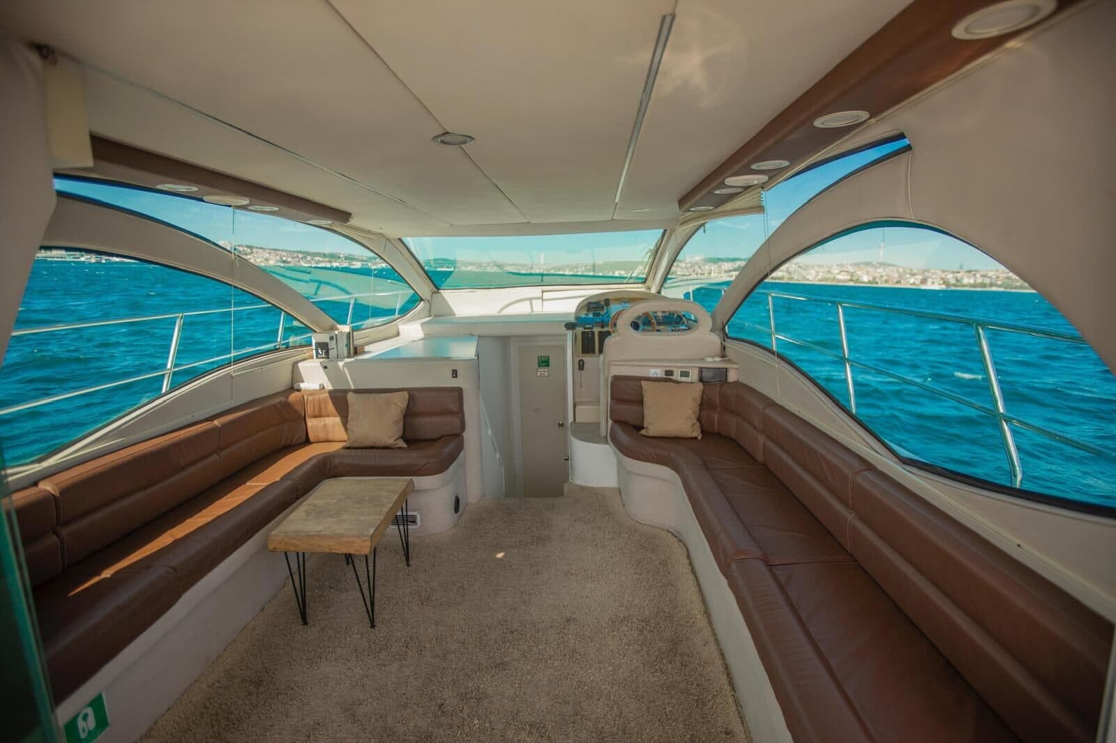 The saloon of a Luma charter yacht, sofas and a low table under wraparound windows
